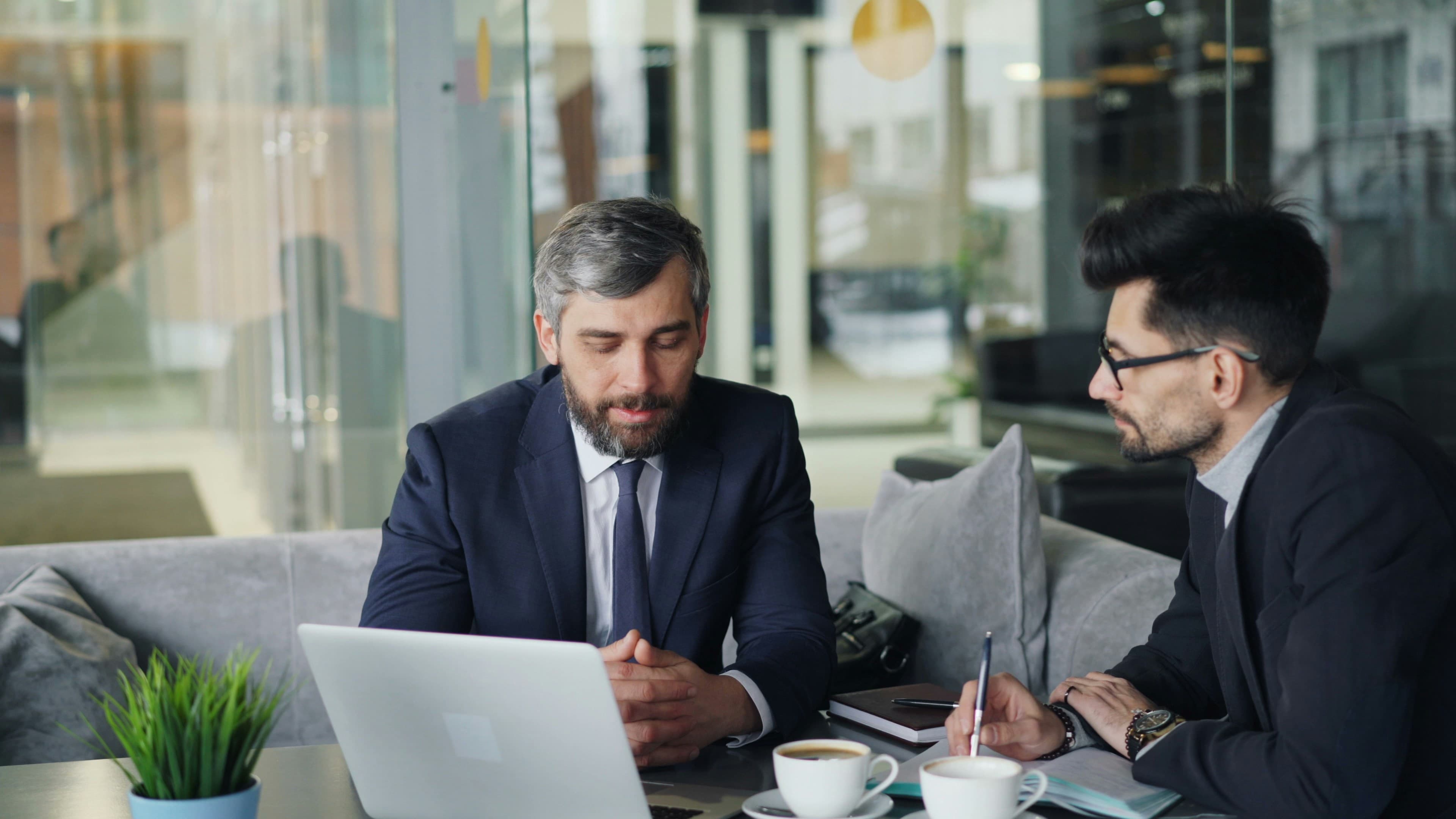 An H2 advisor reviewing figures with a business owner over a laptop