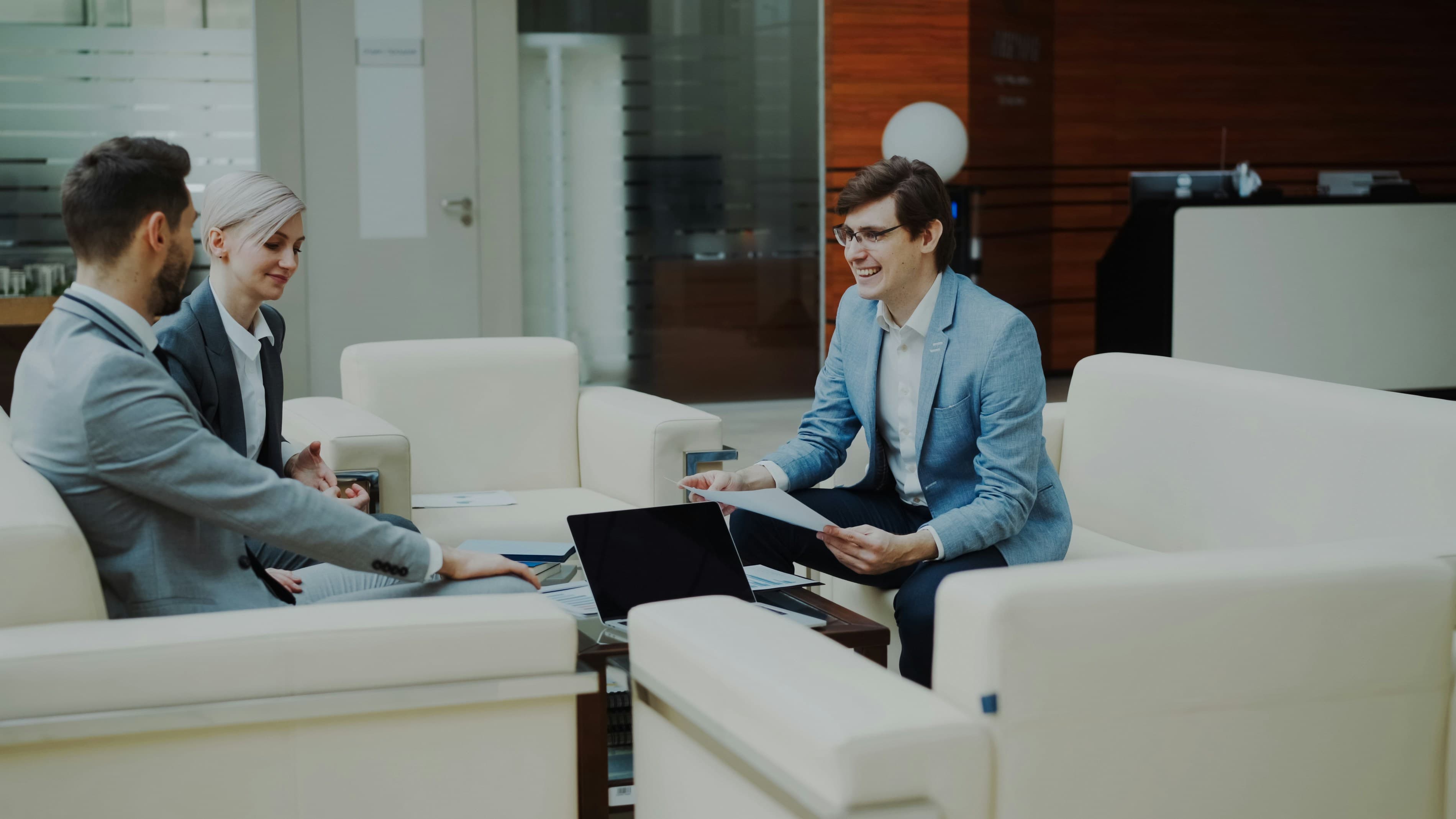 Advisors discussing a plan with clients in a modern office lounge